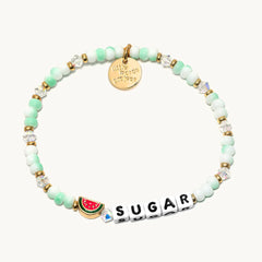 A green colored bracelet with a little watermelon.