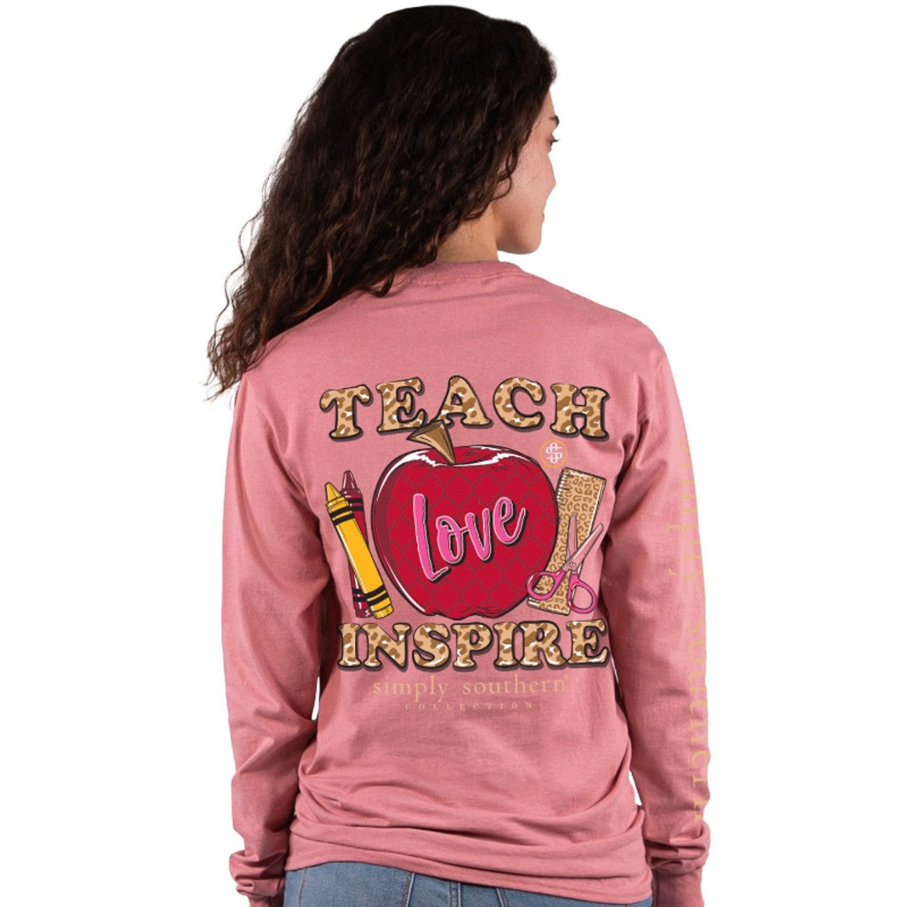 Long sleeve shirt featuring the words "Teach, love and inspire" with classic school supplies such as crowns, scissors and an apple.