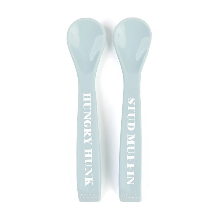 A set of 2 baby spoons in the color blue. One spoon reads, "Hungry Hunk." The other spoon reads, "Stud Muffin." This spoon set comes from the brand Bella Tunno.