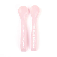 A set of 2 baby spoons in the color pink. One spoon reads, "All Hail The Queen." The other spoon reads, "Little Miss Fabulous ." This spoon set comes from the brand Bella Tunno.