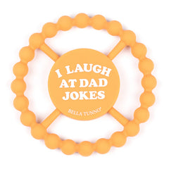 Orange color Happy Teether that reads, "I LAUGH AT DAD JOKES" in the middle. The teether is made from silicone, and comes from the brand Bella Tunno.