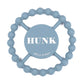 Blue color Happy Teether that reads, "HUNK" in the middle. The teether is made from silicone, and comes from the brand Bella Tunno.