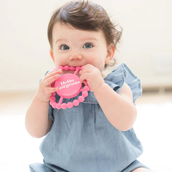 Pink color Happy Teether that reads, "Hello Gorgeous" in the middle. The teether is made from silicone, and comes from the brand Bella Tunno.