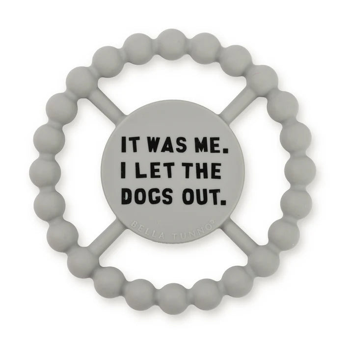 Grey color Happy Teether that reads, "IT WAS ME. I LET THE DOGS OUT" in the middle. The teether is made from silicone, and comes from the brand Bella Tunno.