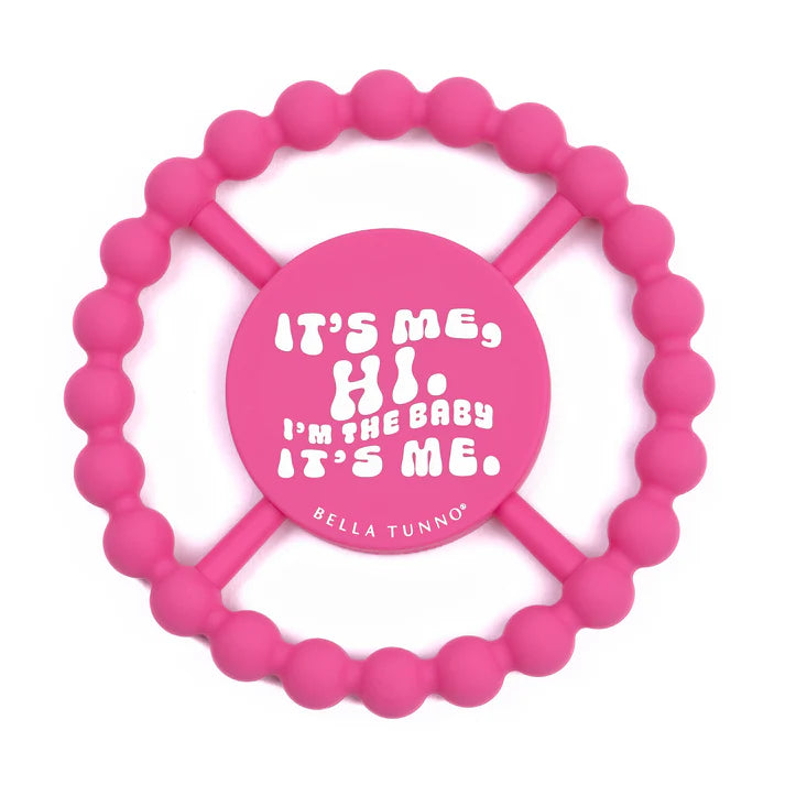 Pink color Happy Teether that reads, "IT'S ME, HI. I'M THE BABY IT'S ME." in the middle. The teether is made from silicone, and comes from the brand Bella Tunno.