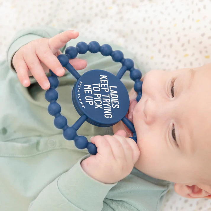 Blue color Happy Teether that reads, "LADIES KEEP TRYING TO PICK ME UP" in the middle. The teether is made from silicone, and comes from the brand Bella Tunno.