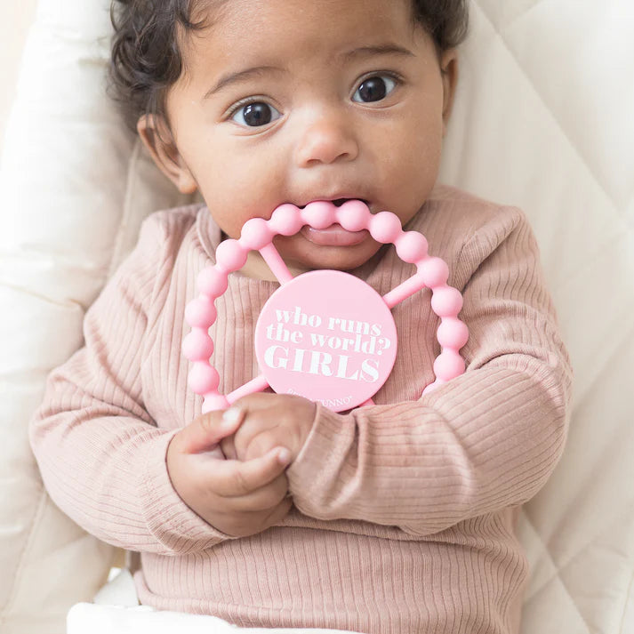 Pink color Happy Teether that reads, "Who runs the world? GIRLS." in the middle. The teether is made from silicone, and comes from the brand Bella Tunno.