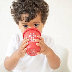 A red color sippy cup, with gray handles. The sippy cup reads, "I'll Drink To That" with the Bella Tunno logo at the bottom.