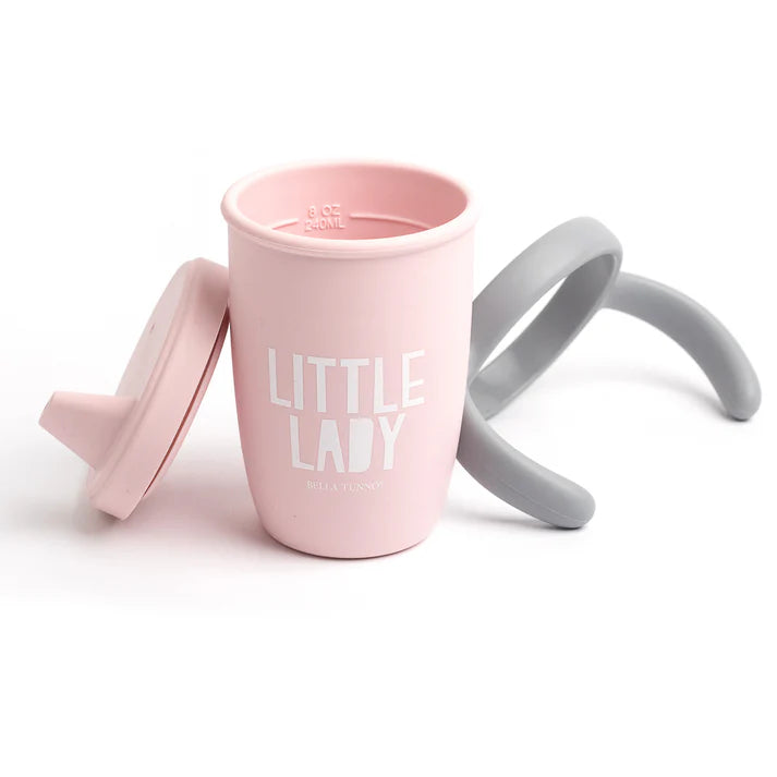 A pink color sippy cup, with gray handles. The sippy cup reads, "Little Lady" with the Bella Tunno logo at the bottom.