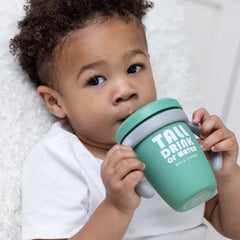 A green color sippy cup, with gray handles. The sippy cup reads, "Tall Drink of Water" with the Bella Tunno logo at the bottom.