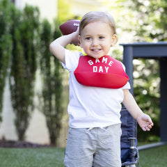 Red color Wonder Bib that reads, "Game Day" with the Bella Tunno logo below it. The bib is adjustable in size with 4 snaps that easily fit around the neck. The Wonder Bib is designed out of silicone, and is made by Bella Tunno.