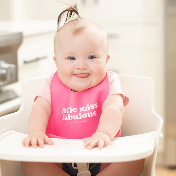 Pink color Wonder Bib that reads, "little miss fabulous" with the Bella Tunno logo below it. The bib is adjustable in size with 4 snaps that easily fit around the neck. The Wonder Bib is designed out of silicone, and is made by Bella Tunno.