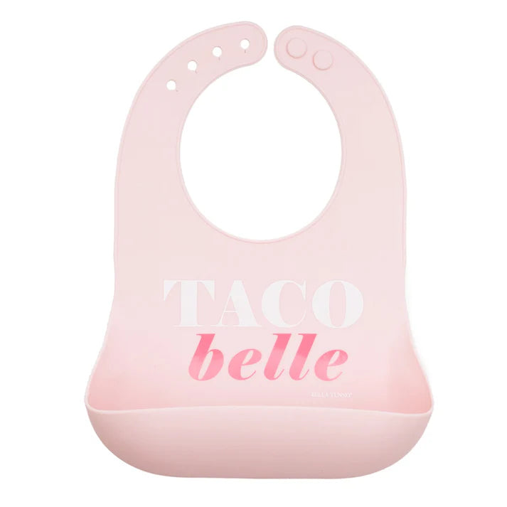 Pink color Wonder Bib that reads, "TACO belle" with the Bella Tunno logo below it. The bib is adjustable in size with 4 snaps that easily fit around the neck. The Wonder Bib is designed out of silicone, and is made by Bella Tunno.