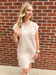 A tan color short sleeve dress that features a front left chest pocket. From Daisy Mercantile.