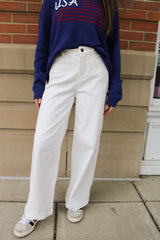 Front view of a white pair of women's pants with wide leg openings at the bottom. These women's pants are from Daisy Mercantile.