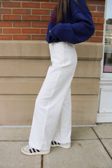 Side view of a white pair of women's pants with wide leg openings at the bottom. These women's pants are from Daisy Mercantile.