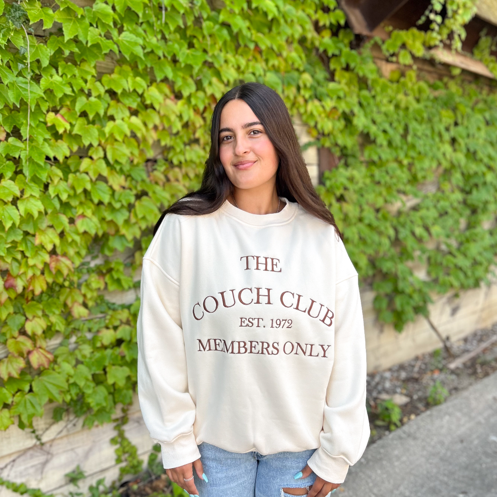 A crewneck sweater that reads, "The couch club est. 1972 members only."