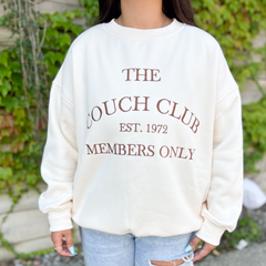 A crewneck sweater that reads, "The couch club est. 1972 members only."