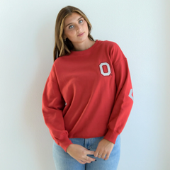 A women wearing a red crewneck sweater, showing the front side of the sweater. The Ohio State block O logo is on the chest of the sweater.