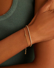 Adjustable gold bracelet with the letter S charm. The bracelet is from the jewelry brand Gorjana.