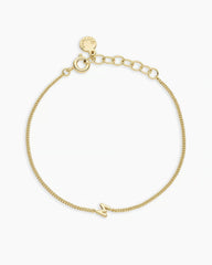 Adjustable gold bracelet with the letter M charm. The bracelet is from the jewelry brand Gorjana.