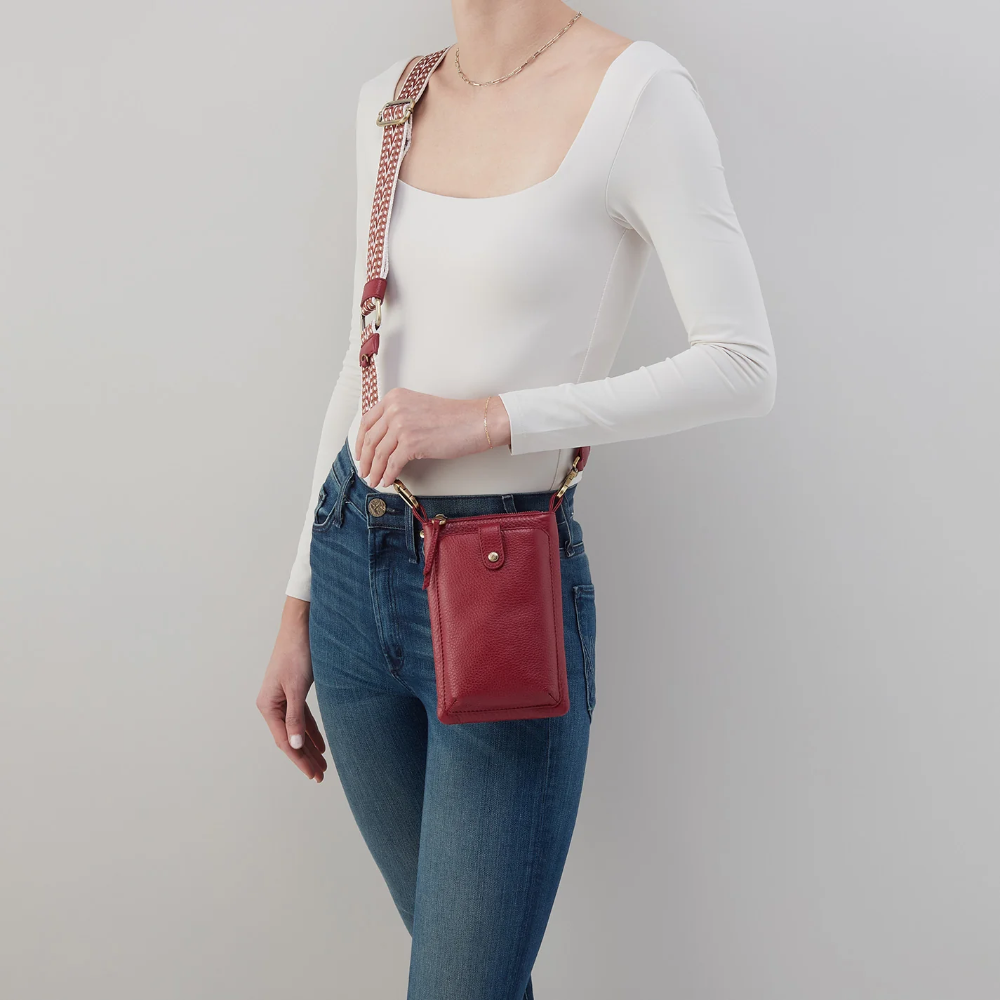 Cass Phone Crossbody in the color wine from the brand HOBO. The phone crossbody is made from pebbled leather.