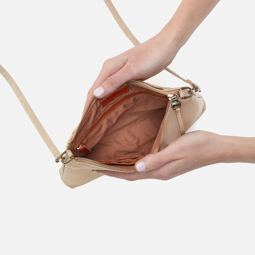 Darcy Crossbody bag designed out of polished leather in the color quartz. This crossbody is from the handbag brand HOBO.