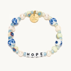 A white and blue beaded bracelet from Little Words project®. With beads that read "HOPE."