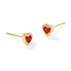 Gold heart shape stud earrings with a red charm in the middle, from the jewelry brand Kendra Scott.