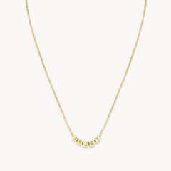 A gold chain necklace from Little Words Project. The necklace includes gold beads that read, TRUST.