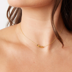 A gold chain necklace from Little Words Project. The necklace includes gold beads that read, TRUST.