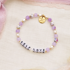 Purple beaded bracelet that reads, Self Love. Designed by Little Words Project.