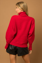 A red turtleneck sweater with the phrase "Merry" in the color white.