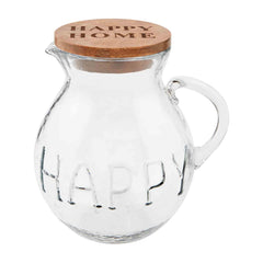 A glass drink pitcher that reads "Happy" on the body, with a brown lid on top that reads, "HAPPY HOME."