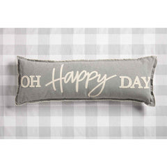 A long grey pillow that reads, "OH HAPPY DAY" in white font, on a white and grey checkered table.