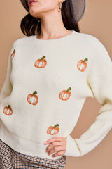 White pullover sweater with orange pumpkins across the front.