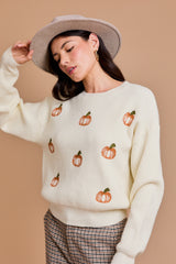 White pullover sweater with orange pumpkins across the front.