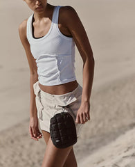 Model wearing a color black quilted travel pouch from the brand Free People Movement on her belt loop.