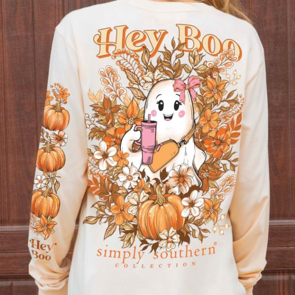 Beige long-sleeve shirt featuring a festive design of a ghost holding a drink amidst autumn flowers and pumpkins, with the text "Hey Boo" from the Simply Southern Brand.