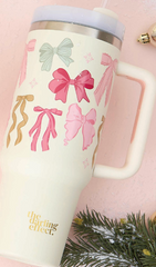 The Darling Effect 40 oz Take Me Everywhere Tumbler in cream with multi colored Christmas bows, and The Darling Effect logo.