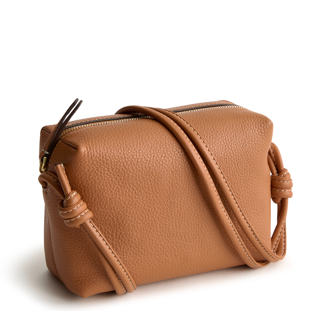 A leather crossbody purse in the color tan, designed by Vera Bradley from the Vera Bradley New Day launch. This crossbody is shown in the Vera Bradley pattern Roasted Pecan.