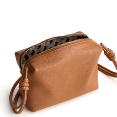 A leather crossbody purse in the color tan, designed by Vera Bradley from the Vera Bradley New Day launch. This crossbody is shown in the Vera Bradley pattern Roasted Pecan.