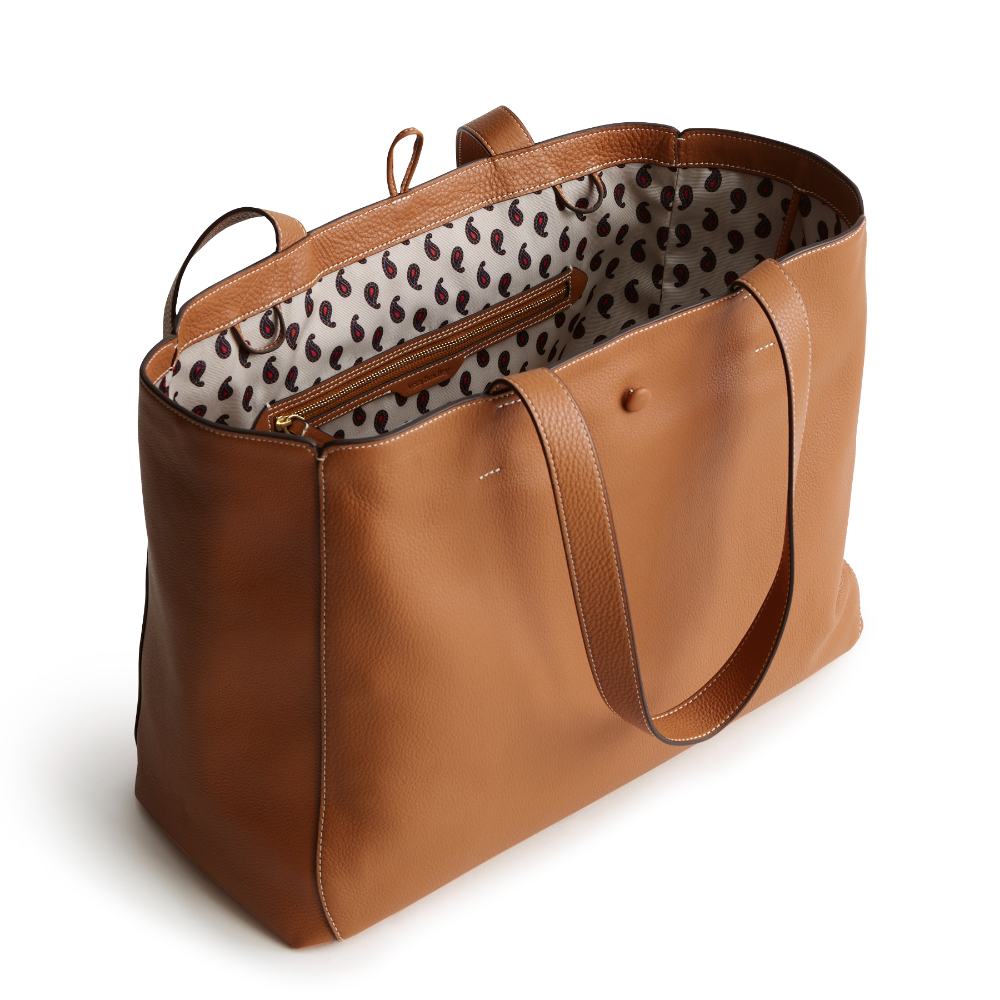 A tan color tote bag from Vera Bradley New Day launch. The tote bag is made out of leather, and is shown in the Vera Bradley Pattern Roasted Pecan.
