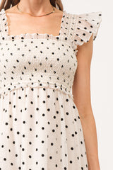 White midi dress with no sleeves, with black polkadots all over.