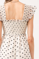 White midi dress with no sleeves, with black polkadots all over.