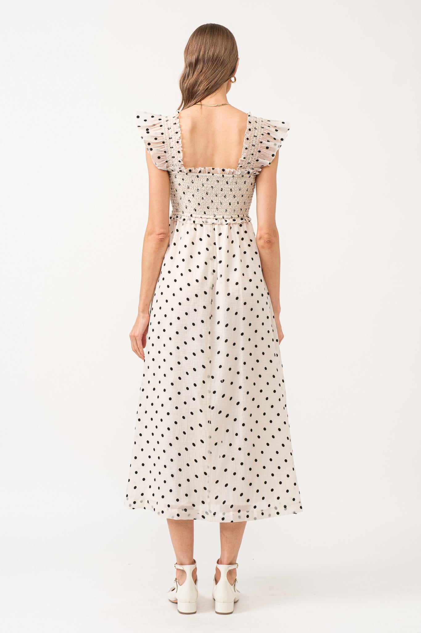 White midi dress with no sleeves, with black polkadots all over.