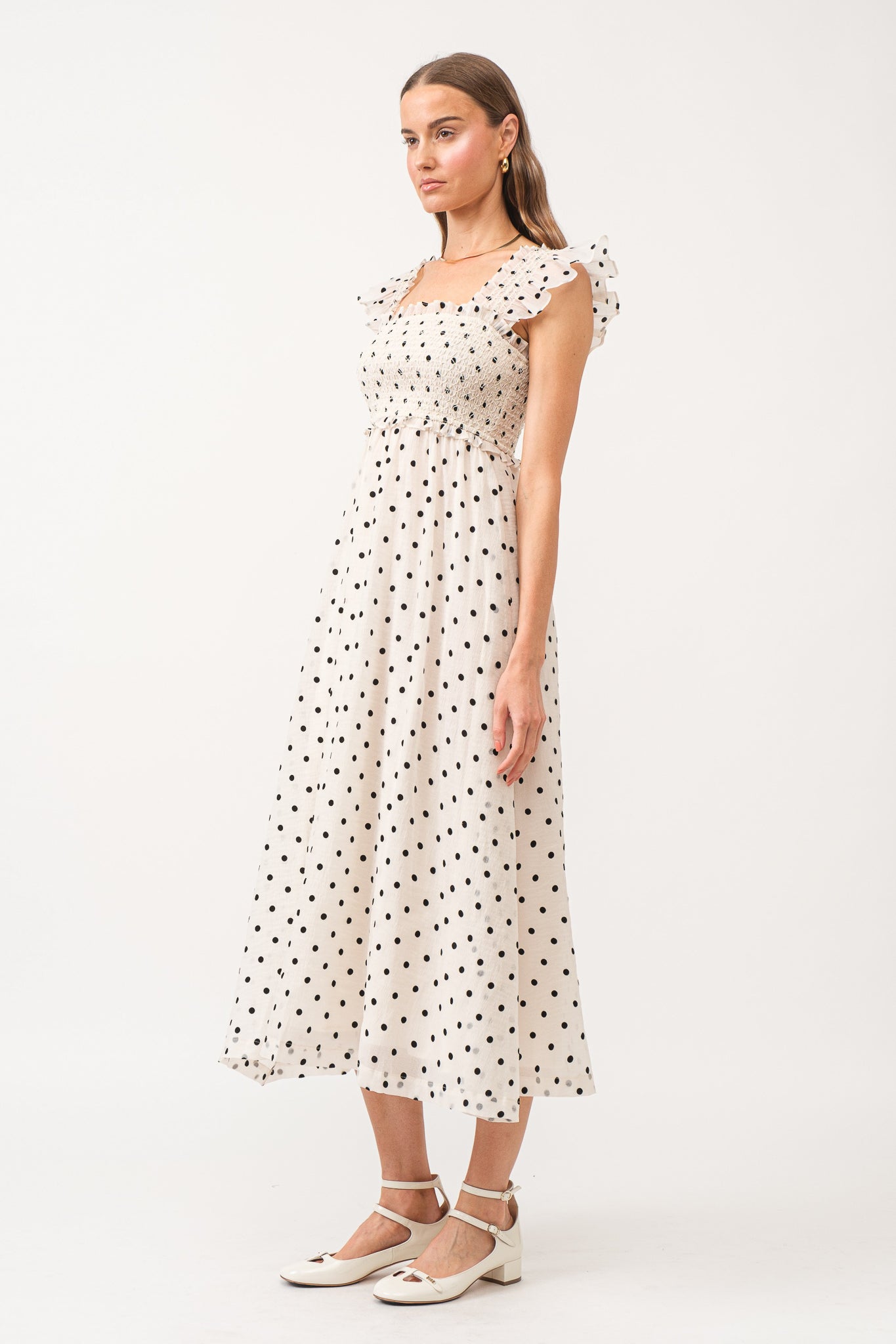 White midi dress with no sleeves, with black polkadots all over.