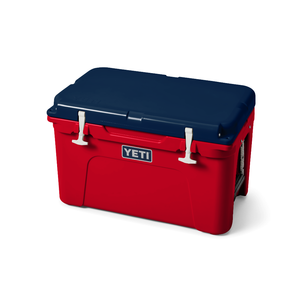 The limited edition 2024 Tundra 45 YETI Cooler with the lid closed. The lid is the color navy blue. The base of the cooler is red, and the secure straps on the lid are white. The front of the cooler showcases a classic YETI logo.