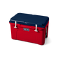 The limited edition 2024 Tundra 45 YETI Cooler with the lid closed. The lid is the color navy blue. The base of the cooler is red, and the secure straps on the lid are white. The front of the cooler showcases a classic YETI logo.