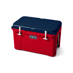 The limited edition 2024 Tundra 45 YETI Cooler with the lid closed. The lid is the color navy blue. The base of the cooler is red, and the secure straps on the lid are white. The front of the cooler showcases a classic YETI logo.